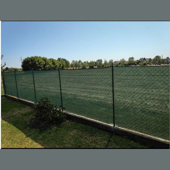 Telo ombreggiante 90% verde installato su recinzione da giardino per garantire privacy e protezione dal vento.