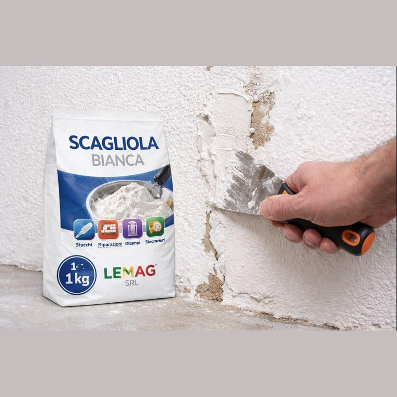 Applicazione di gesso scagliola per stuccature su una crepa nel muro con spatola, accanto al sacco di Scagliola Bianca Lemag da 1 kg.