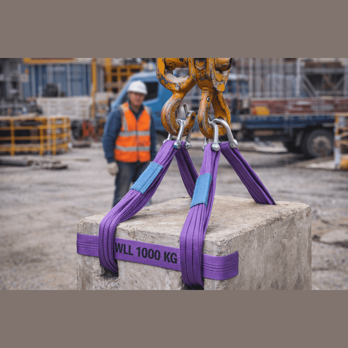 Uso di una fascia di sollevamento 1 tonnellata viola con asole per sollevare un blocco di cemento da 1000 kg in un cantiere.