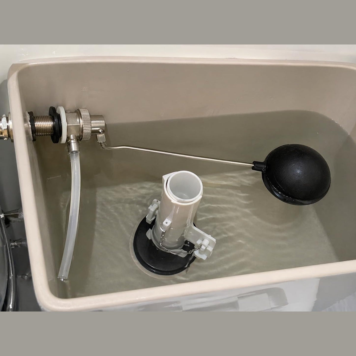 Dettaglio di una valvola a galleggiante tipo catis con sfera nera per la regolazione dell'acqua in una cassetta di scarico.