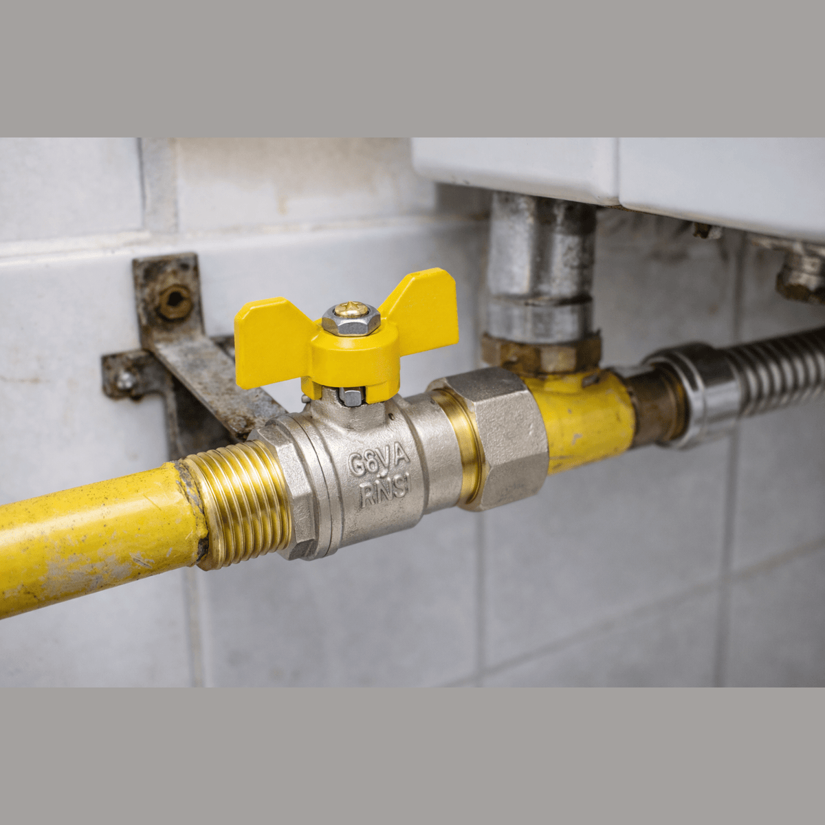 Dettaglio di una valvola a sfera gas 3/4 in ottone con maniglia gialla installata su un impianto domestico.