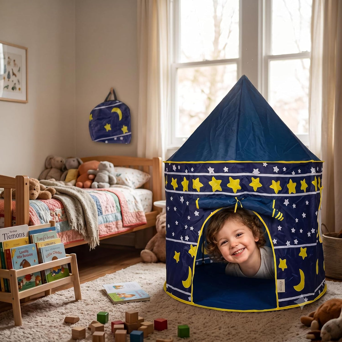 Un bimbo felice gioca nella tenda gioco per bambini blu a forma di castello con stelle in cameretta.