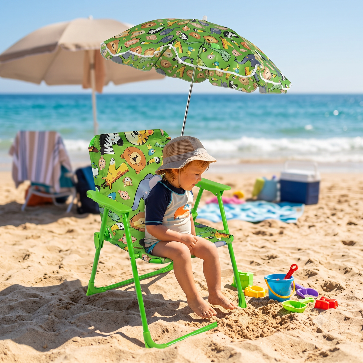 Bimbo seduto su una sedia da spiaggia per bambini con ombrellino verde sulla sabbia.