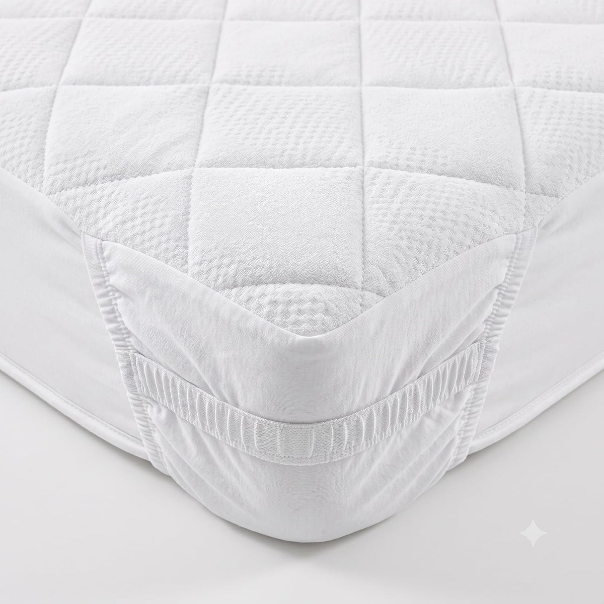 Dettaglio dell'angolo elastico di un coprimaterasso matrimoniale 180x200 in morbido tessuto jacquard trapuntato bianco.